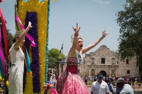 Miss Fiesta San Antonio holds up her hands in a "rock on" gesture at the Battle of Flowers Parade.